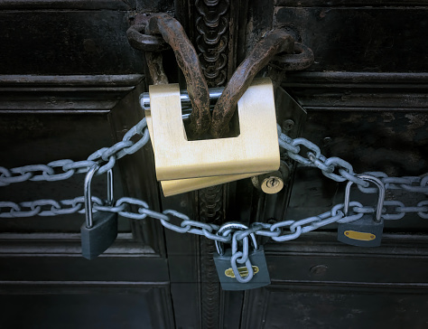 Old wood doors with iron hardware, chain and spike closure. Wood plank slides across both doors, held by iron brackets to lock the doors and hold off an intruder. Medieval fortress doors