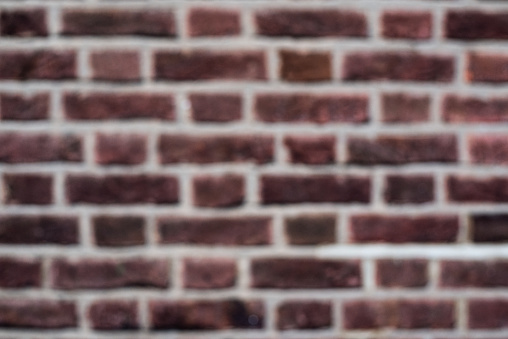 Textured background of shabby dark red colored brick wall with white lines between stones
