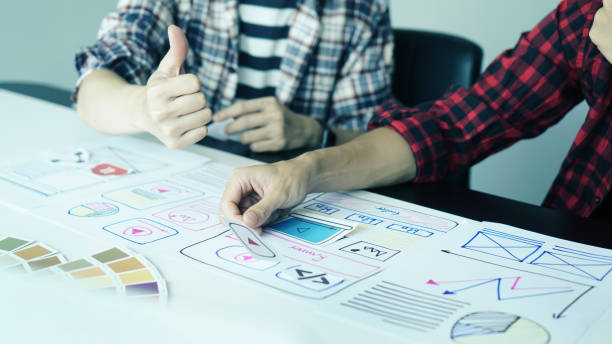 istock Designers man drawing ui/ux designers working and designing user interface for website and application, working together with partner planning and brainstorming sketch designs with computer laptop. 1224932674