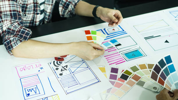 istock Designers man drawing ui/ux designers working and designing user interface for website and application, working together with partner planning and brainstorming sketch designs with computer laptop. 1224932680