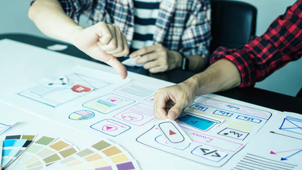 istock Designers man drawing ui/ux designers working and designing user interface for website and application, working together with partner planning and brainstorming sketch designs with computer laptop. 1224932684