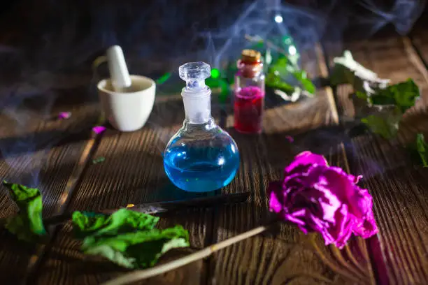 Photo of Witchcraft. Witch doctor desk table. Magic potion. ALternative medicine concept. Divination, love potion. Mysterious clouds of smoke