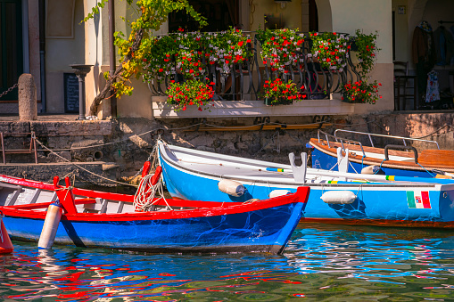 Fishing colorful boats floating on water - pier in Limone Sul Garda, Italy