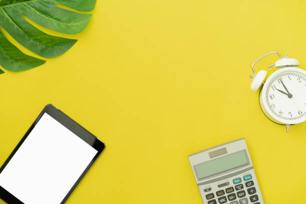 istock Top view modern digital tablet and calculator with alarm clock on yellow color background. 1224950657
