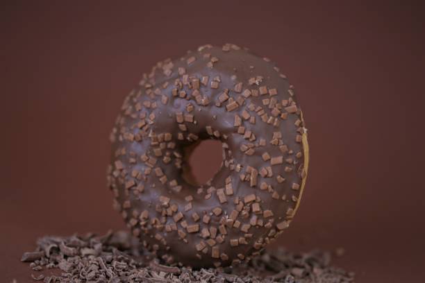 istock Chocolate donut on grated chocolate on a bright brown background.Baking and sweets. Sweet dough dessert.Donut with chocolate icing and chocolate chips 1224951256