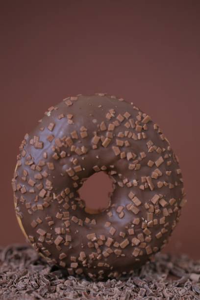 istock Chocolate donut on grated chocolate on a brown background.Baking and sweets. Sweet dough dessert.Donut with chocolate icing and chocolate chip 1224951278