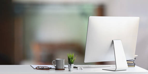 istock Workspace computer putting on white working desk and surrounded by coffee cup, clipboard, potted plant, stack of books, glasses, keyboard and earphones. Orderly workspace concept. 1224959783