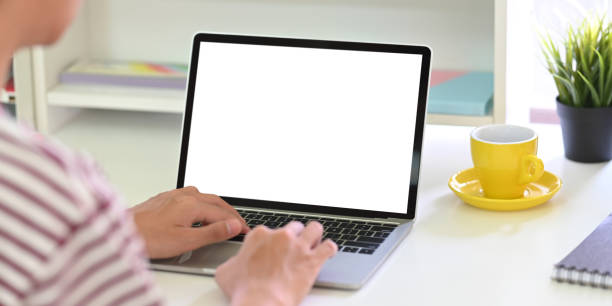 istock Back shot of smart man typing on white blank screen computer laptop that putting on white working desk and surrounded by coffee cup, potted plant and stationary. 1224960064