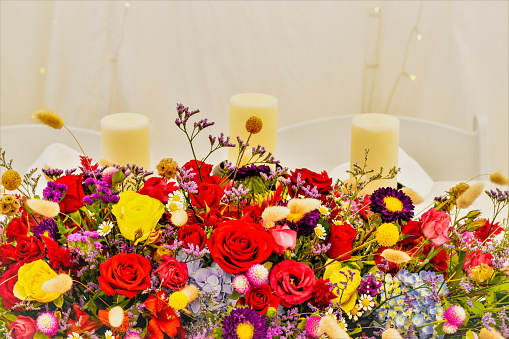 Candles and colorful floral arrangement against a white background