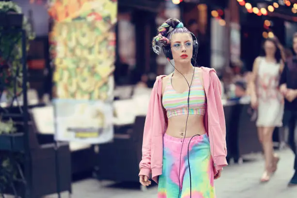 Avant-garde confident young woman with trendy eyeglasses and piercings, listening music on headphones