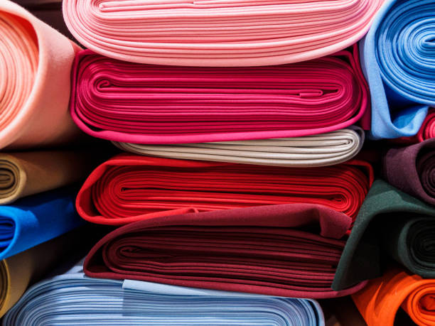 istock Rolls of bright multicolored fabric close-up. Many different fabrics are rolled up and lying on the shelves. Samples of different natural fabrics in the warehouse of the fabric factory 1224964058