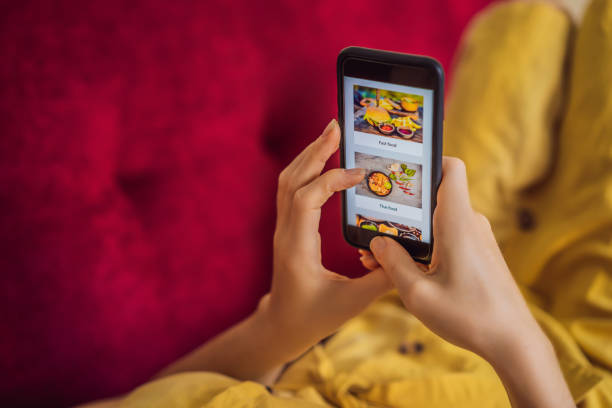 una joven pide comida para el almuerzo en línea usando un teléfono inteligente - red meat fotografías e imágenes de stock