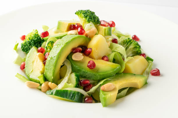 istock Green Salad with Avocado, Cucumber and Nuts on White Plate 1224967262
