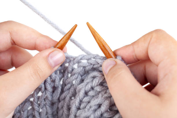 istock Women's hands knit from grey wool on white background. Hand knitting 1224969603