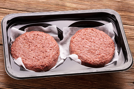 minced meat substitutes for burger in plastic package on wooden background