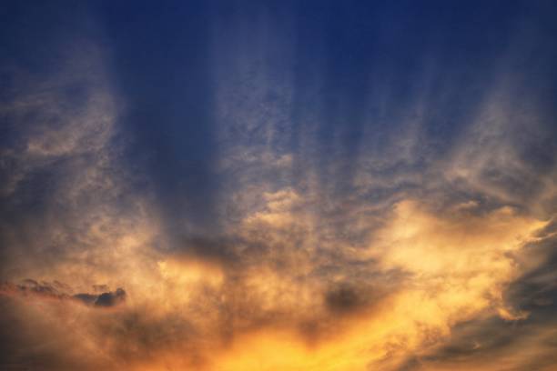bursting sky. light ray shining through the clouds. cloud caught by last light of the day and grow warm orange yellow in a dramatic fashion. hope God inspiration and silver linings concepts.