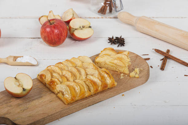 istock Portion of apple pie on wooden cutting board with various ingredients. Cinnamon sticks and luster sugar. 1224974925