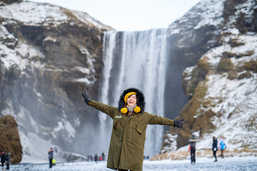 Young asian woman arms outstretched near waterfall