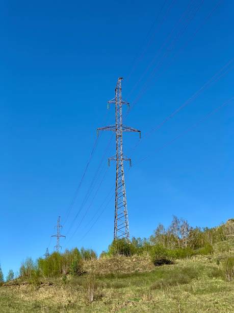 istock High voltage power stations standing in a field among green grass on a hill 1224978192