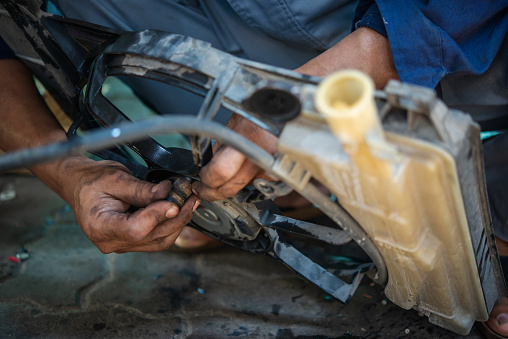 Hands of car mechanic holding the fan of Radiator in garage. Car repair