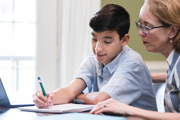 istock Homeschooling mother watches as son works math problem 1224983499