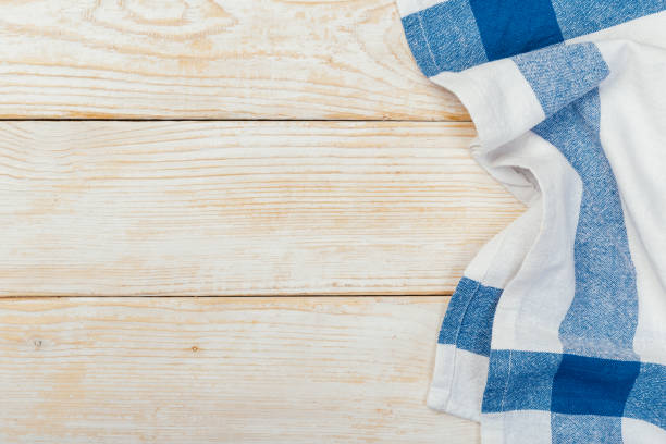 istock Top view on a white wooden table with a linen kitchen towel or textile napkin. a tablecloth on a light wood countertop. Copy space for text. 1224984143