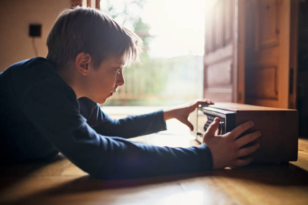 Little boy spending time in old wooden cabin in mountains. The boy have found an interesting old radio and is examining it.

Nikon D850