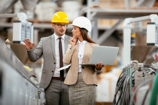 istock Two professional people with helmets working in quality control in factory production line. 1224986457