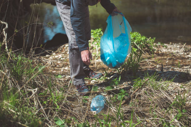 istock Man picking up plastic bottle, garbage collecting in the forest cleaning planet, help garbage collection charity environment 1224986707