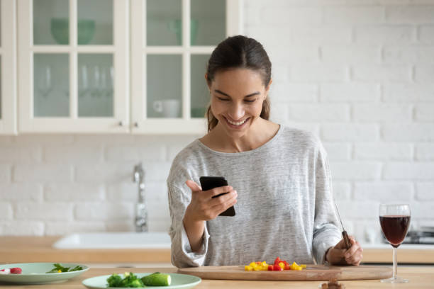 istock Smiling woman using smartphone, cooking salad, healthy snack 1224986904