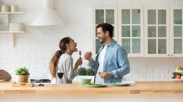 istock Happy loving couple singing, having fun with kitchenware in kitchen 1224986907