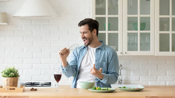 istock Funny young man singing into whisk, cooking in modern kitchen 1224986911