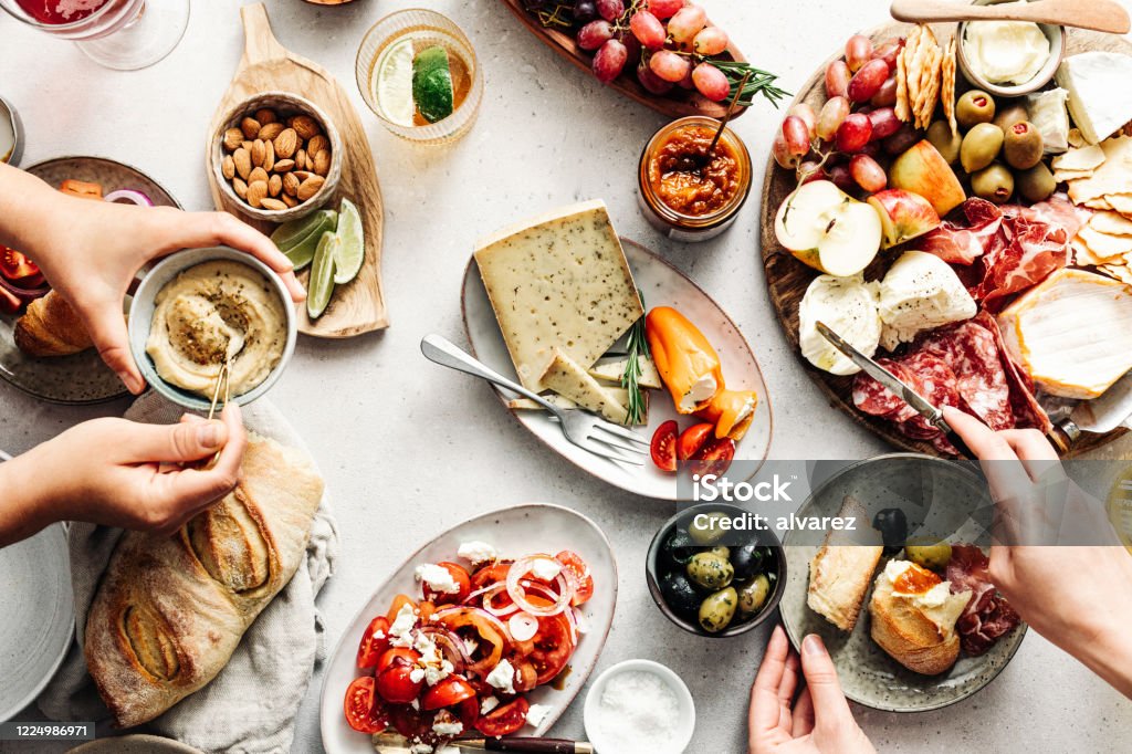 Women eating fresh Mediterranean platter on table High angle view of fresh meal on table. Women are eating healthy food. They are with Mediterranean platter. Food Stock Photo