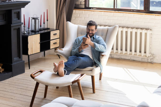 istock Smiling young man using smartphone, sitting in armchair 1224986990