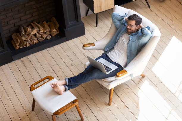istock Peaceful young man resting in armchair with laptop 1224987500