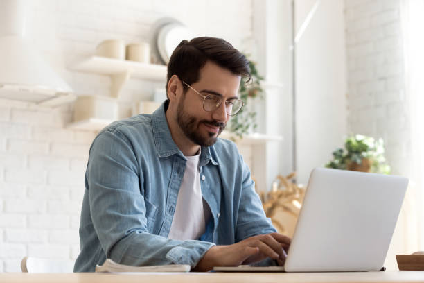 istock Focused young man wearing glasses using laptop, typing on keyboard 1224987515