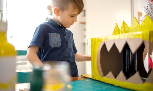 istock Boy painting a cardboard dinosaur costume 1224990138
