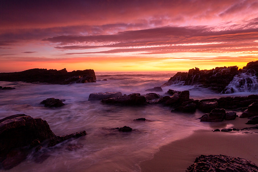 Magnificent red and yellow skies over the splendid rocky beach coast of Merimbula on the Sapphire Coast of NSW Australia.  A wonderful travel destination