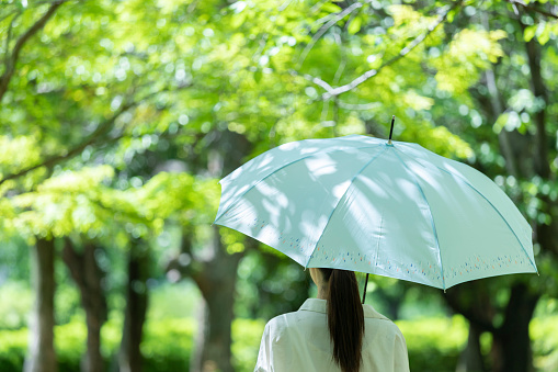 Young woman with an umbrella in the fresh green