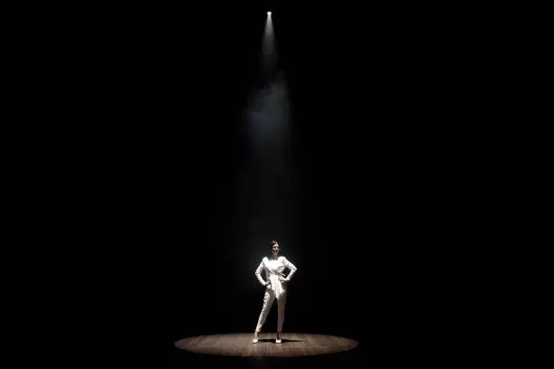 Photo of model in a white suit on stage in a beam of white light
