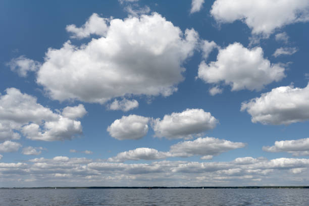 Majestic cumulus cloudscape background with blue sky and white clouds over lake.