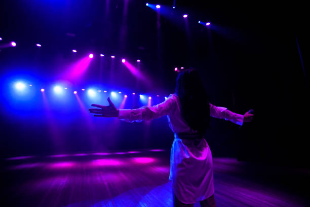 istock Unrecognizable singer standing on stage at microphone, back view, neon lights 1225002318