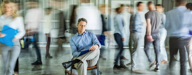 istock Panoramic view of a businessman writing reports surrounded by his colleagues in blurred motion. 1225002623