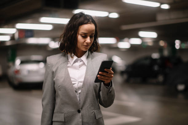 istock Businesswoman in garage unlocking car and using phone 1225002639