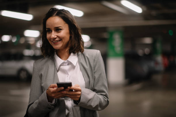 istock Businesswoman in garage unlocking car and using phone 1225002674