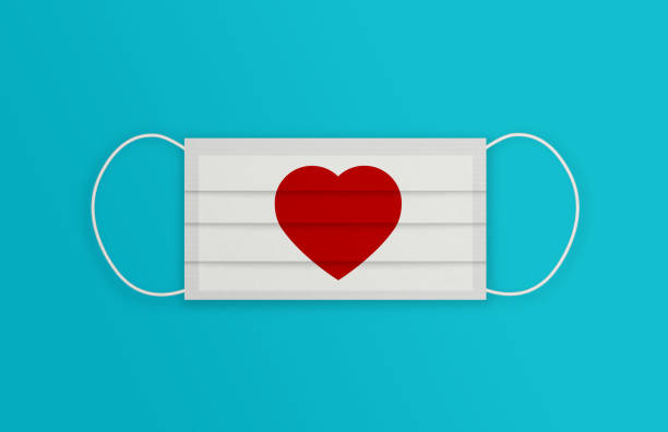 istock White Protective Mask with Heart Shape over the blue background. 1225009054