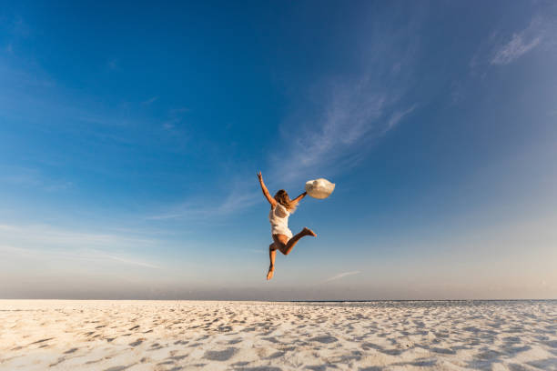 istock Carefree woman having fun while jumping on the beach. 1225009384