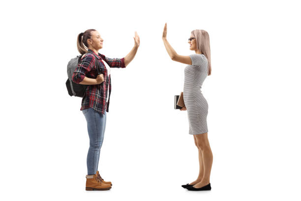 istock Female student gesturing high-five with a woman holding books 1225010237