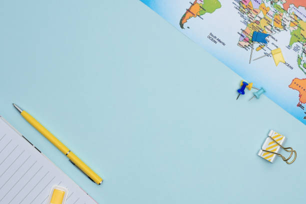 Travel planning flat lay with copy space. Stationary items and map on blue background top view.