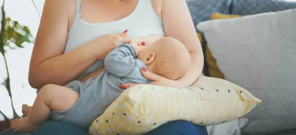 Front view of unrecognizable woman breastfeeding her child.